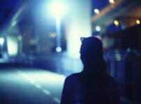 青い光に照らされた夜の街をひとり歩く人物の後ろ姿｜懐かしい情景が静かによみがえる、やさしい記憶のイメージ写真