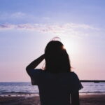 夕暮れの海辺でひとり佇む人物のシルエット｜懐かしい情景が静かによみがえる、やさしい記憶のイメージ写真