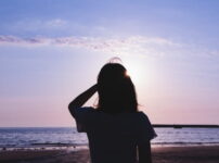 夕暮れの海辺でひとり佇む人物のシルエット｜懐かしい情景が静かによみがえる、やさしい記憶のイメージ写真