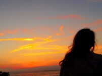 夕暮れの海辺で女性が静かに佇む後ろ姿の情景｜懐かしい情景が静かによみがえる、やさしい記憶のイメージ写真