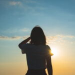 夕暮れの光に照らされながら静かに佇む女性のシルエット｜懐かしい情景が静かによみがえる、やさしい記憶のイメージ写真