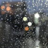 雨粒がついた窓越しに、ぼんやりと街の灯りがにじむ夜の情景｜懐かしい情景が静かによみがえる、やさしい記憶のイメージ写真
