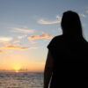 夕暮れの海辺で女性が静かに佇むシルエットの風景｜懐かしい情景が静かによみがえる、やさしい記憶のイメージ写真
