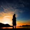 夕暮れの海辺で女性が静かに佇むシルエットの風景｜懐かしい情景が静かによみがえる、やさしい記憶のイメージ写真
