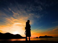 夕暮れの海辺で女性が静かに佇むシルエットの風景｜懐かしい情景が静かによみがえる、やさしい記憶のイメージ写真