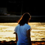夕暮れの水辺で静かに佇む女性の横顔｜懐かしい情景が静かによみがえる、やさしい記憶のイメージ写真
