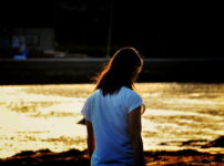 夕暮れの水辺で静かに佇む女性の横顔｜懐かしい情景が静かによみがえる、やさしい記憶のイメージ写真