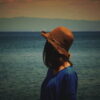 夕暮れの水辺を静かに見つめる女性の後ろ姿｜懐かしい情景が静かによみがえる、やさしい記憶のイメージ写真