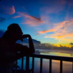 夕暮れの海を静かに見つめる人物のシルエット｜懐かしい情景が静かによみがえる、やさしい記憶のイメージ写真