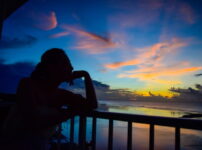 夕暮れの海を静かに見つめる人物のシルエット｜懐かしい情景が静かによみがえる、やさしい記憶のイメージ写真
