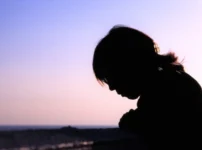 夕暮れの空を背景に、大人の女性のシルエットが静かに佇む情景｜懐かしい情景が静かによみがえる、やさしい記憶のイメージ写真